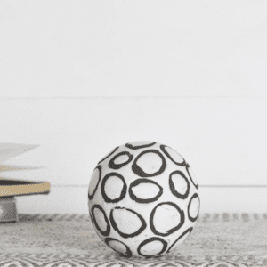 Decorative white ball with black circles on a patterned surface.